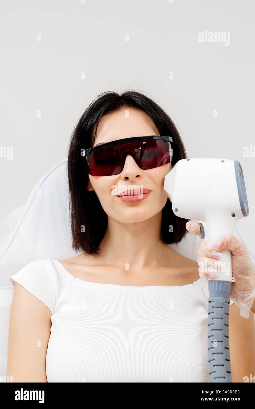 Die Therapeutin/Kosmetikerin führt eine Laserbehandlung auf dem Gesicht einer Frau in einer Schönheitsklinik durch. Nahaufnahme. Das Konzept der Werbung gesund Stockfoto Die Therapeutin/Kosmetikerin führt eine Laserbehandlung auf dem Gesicht einer Frau in einer Schönheitsklinik durch. Nahaufnahme. Das Konzept der Werbung gesund Stockfoto