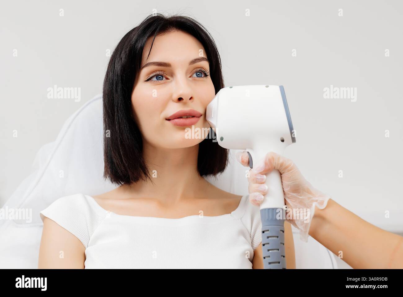 Die Therapeutin/Kosmetikerin führt eine Laserbehandlung auf dem Gesicht einer Frau in einer Schönheitsklinik durch. Nahaufnahme. Das Konzept der Werbung gesund Stockfoto Die Therapeutin/Kosmetikerin führt eine Laserbehandlung auf dem Gesicht einer Frau in einer Schönheitsklinik durch. Nahaufnahme. Das Konzept der Werbung gesund Stockfoto