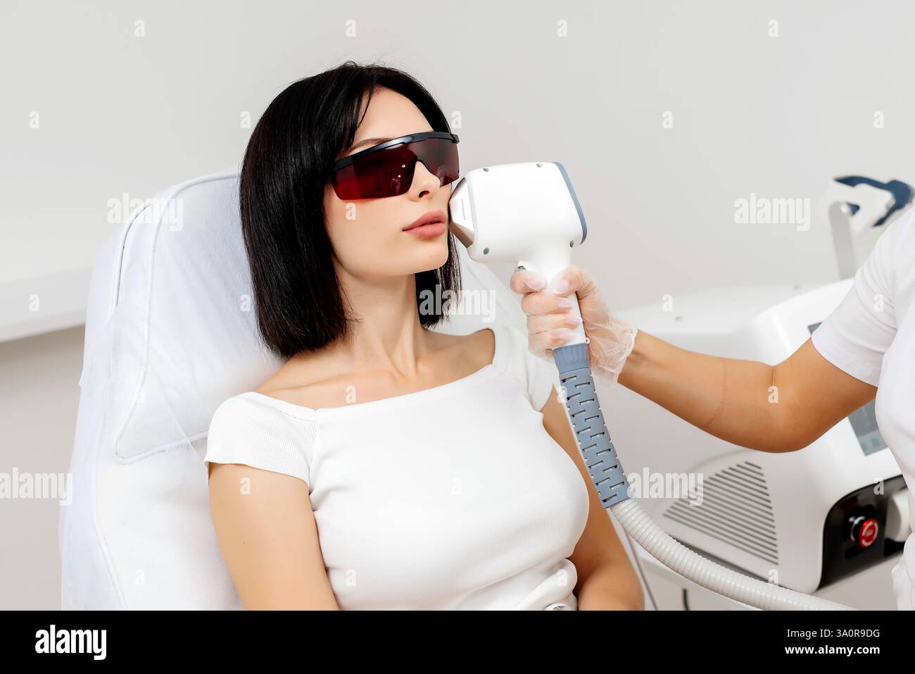 Die Therapeutin/Kosmetikerin führt eine Laserbehandlung auf dem Gesicht einer Frau in einer Schönheitsklinik durch. Nahaufnahme. Das Konzept der Werbung gesund Stockfoto Die Therapeutin/Kosmetikerin führt eine Laserbehandlung auf dem Gesicht einer Frau in einer Schönheitsklinik durch. Nahaufnahme. Das Konzept der Werbung gesund Stockfoto