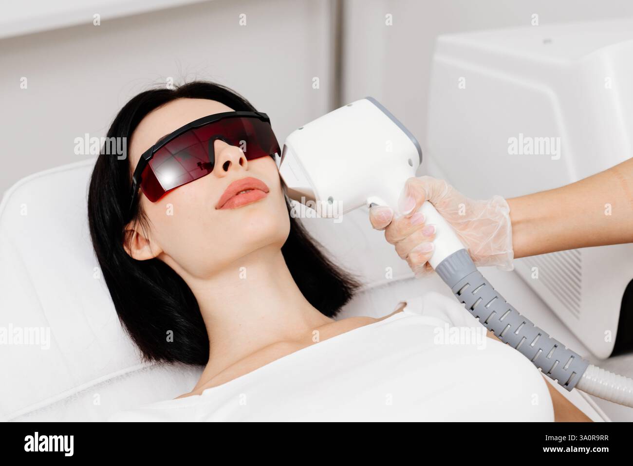 Die Therapeutin/Kosmetikerin führt eine Laserbehandlung auf dem Gesicht einer Frau in einer Schönheitsklinik durch. Nahaufnahme. Das Konzept der Werbung gesund Stockfoto Die Therapeutin/Kosmetikerin führt eine Laserbehandlung auf dem Gesicht einer Frau in einer Schönheitsklinik durch. Nahaufnahme. Das Konzept der Werbung gesund Stockfoto