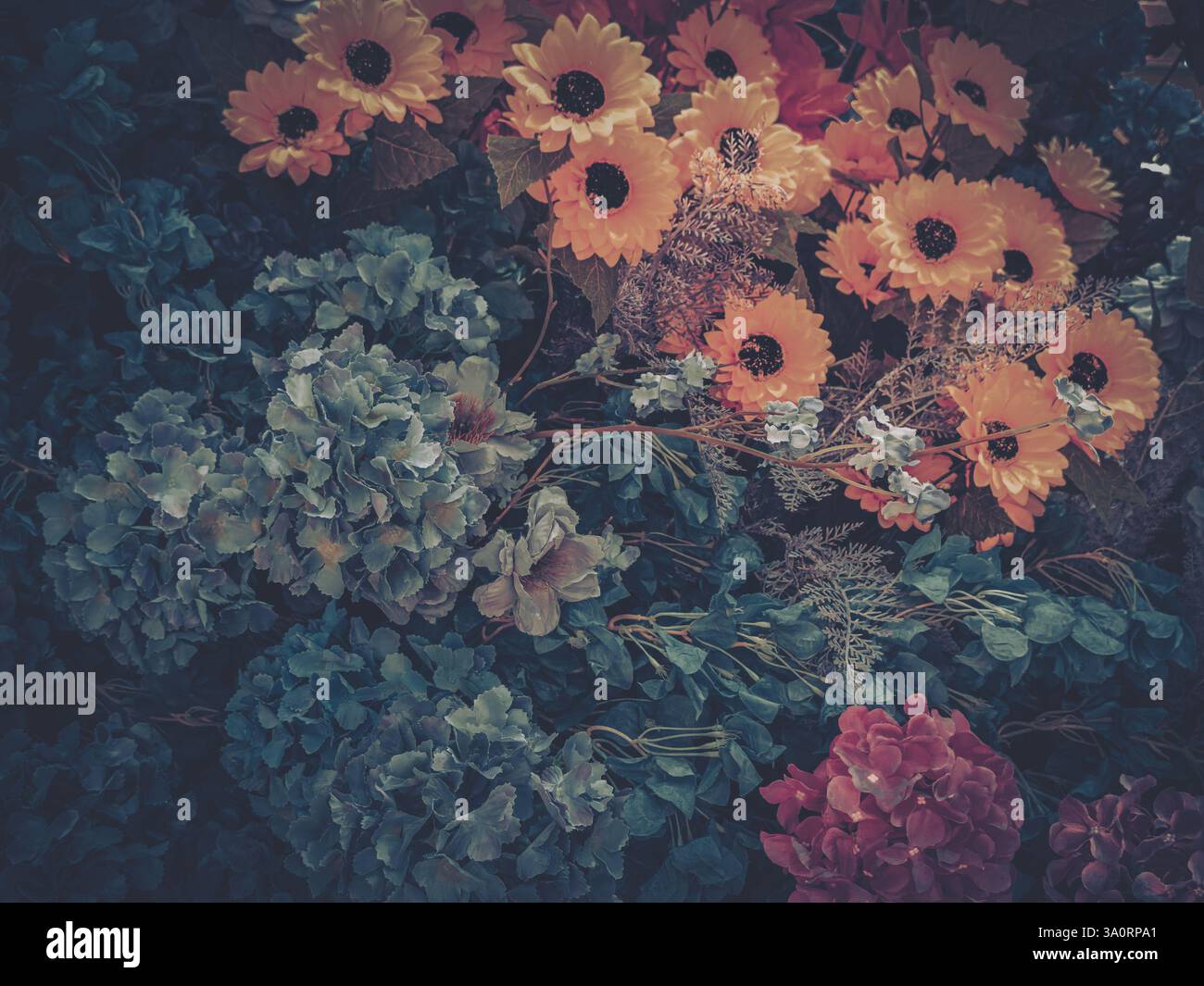 Farbenfrohe künstliche Blumen in Blüte sorgen für ein lebendiges und dekoratives Display. Die Vielfalt der Blumenelemente verleiht dem ein visuelles Interesse und eine Textur Stockfoto