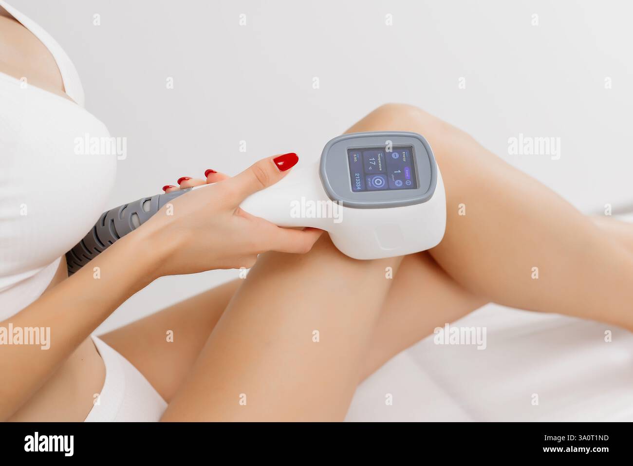 Ein Dermatologe steht mit Geräten zur Haarentfernung. Der Kosmetiker passt die Geräteeinstellungen für die Haarentfernung mit dem Laser an Stockfoto Ein Dermatologe steht mit Geräten zur Haarentfernung. Der Kosmetiker passt die Geräteeinstellungen für die Haarentfernung mit dem Laser an Stockfoto