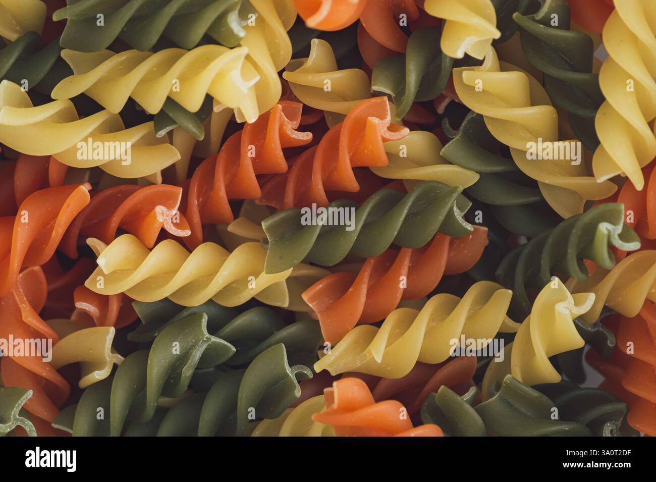 Farbenfroher Essenshintergrund mit natürlichem, mehrfarbigem Fusilli. Minimales Nudelkonzept. Kreatives kulinarisches Muster im Hintergrund. Pasta-Ästhetik. Flache Lagen. Stockfoto