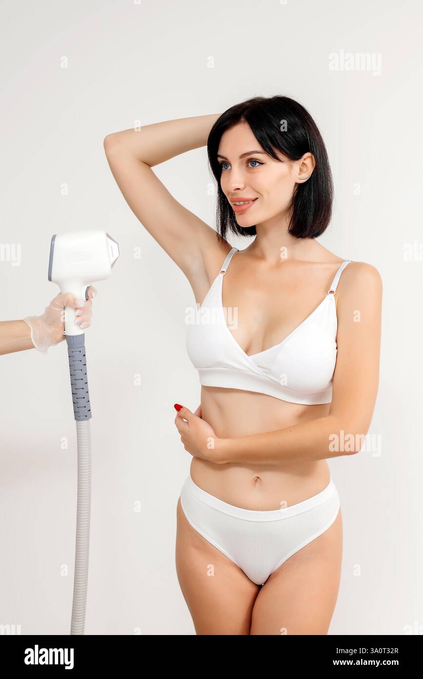 Ein Dermatologe steht mit Geräten zur Haarentfernung. Der Kosmetiker passt die Geräteeinstellungen für die Haarentfernung mit dem Laser an Stockfoto