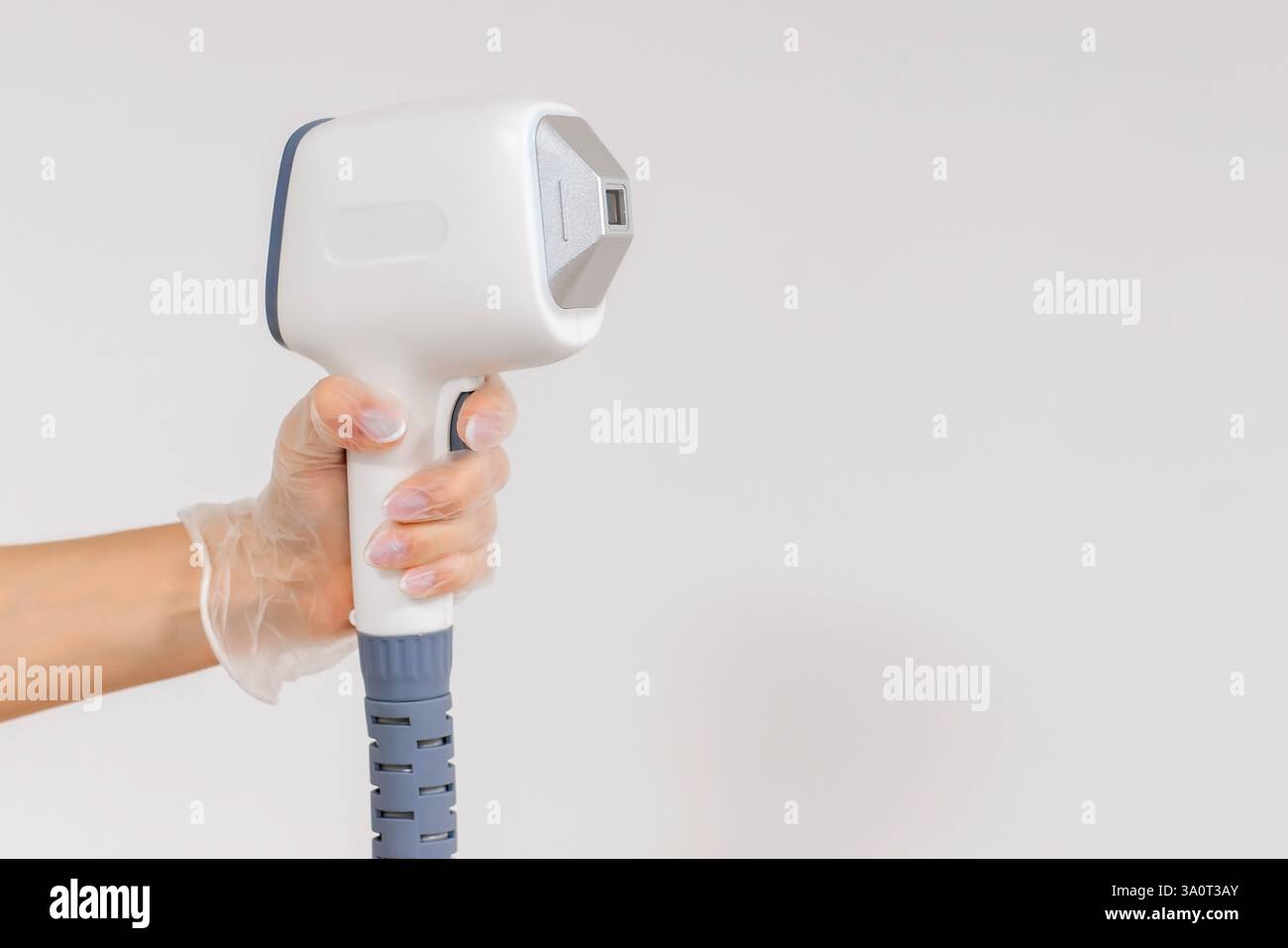 Ein Dermatologe steht mit Geräten zur Haarentfernung. Der Kosmetiker passt die Geräteeinstellungen für die Haarentfernung mit dem Laser an Stockfoto Ein Dermatologe steht mit Geräten zur Haarentfernung. Der Kosmetiker passt die Geräteeinstellungen für die Haarentfernung mit dem Laser an Stockfoto