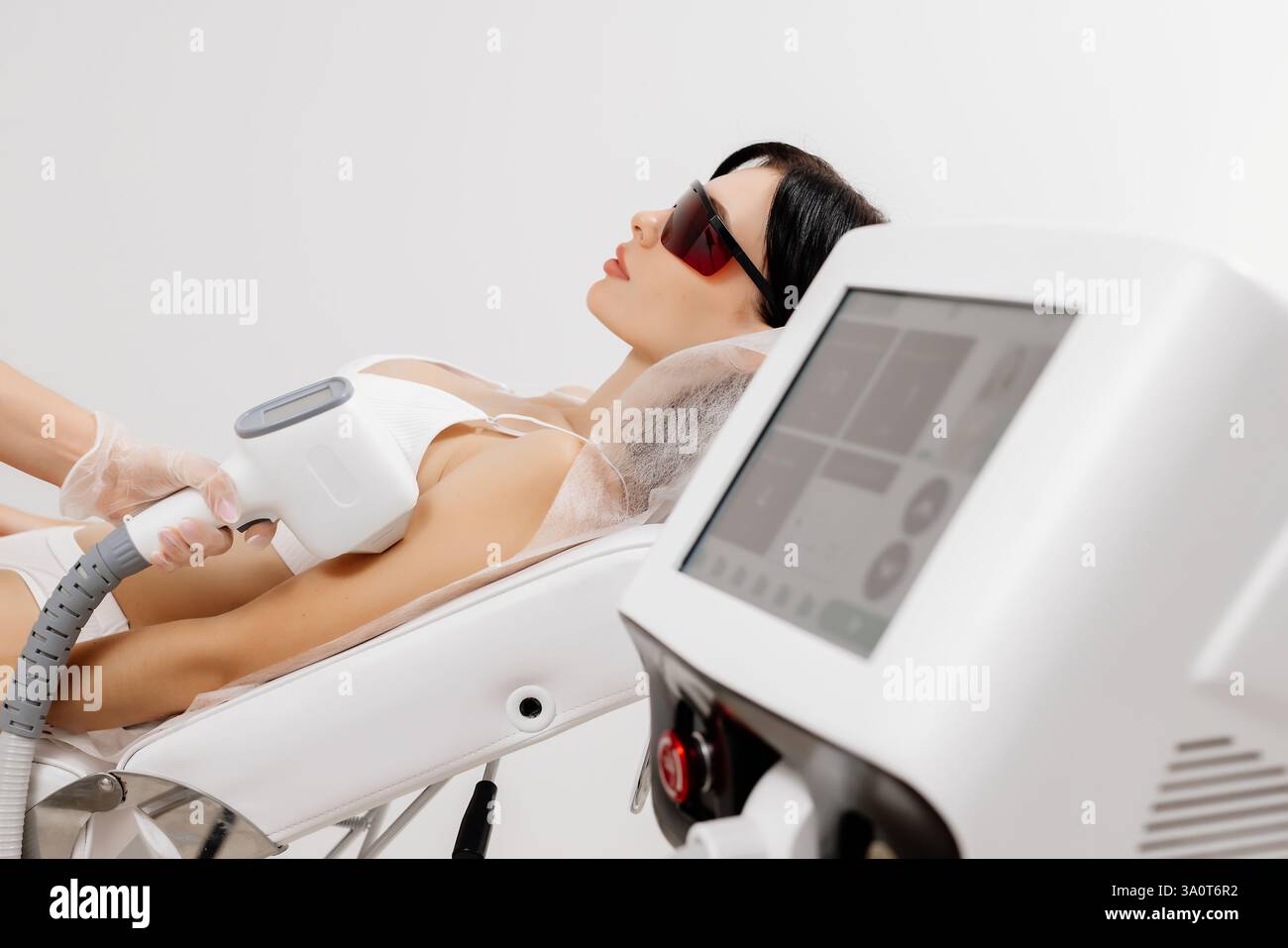 Körperhygiene. Laserhaarentfernung des Körpers. Ein Kosmetiker entfernt Körperhaare junger Frauen. Laserhaarentfernung in einer Kosmetikklinik. Stockfoto Körperhygiene. Laserhaarentfernung des Körpers. Ein Kosmetiker entfernt Körperhaare junger Frauen. Laserhaarentfernung in einer Kosmetikklinik. Stockfoto