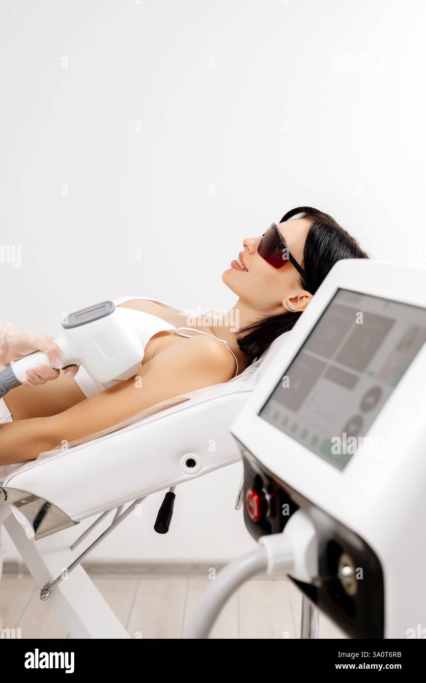 Körperhygiene. Laserhaarentfernung des Körpers. Ein Kosmetiker entfernt Körperhaare junger Frauen. Laserhaarentfernung in einer Kosmetikklinik. Stockfoto Körperhygiene. Laserhaarentfernung des Körpers. Ein Kosmetiker entfernt Körperhaare junger Frauen. Laserhaarentfernung in einer Kosmetikklinik. Stockfoto
