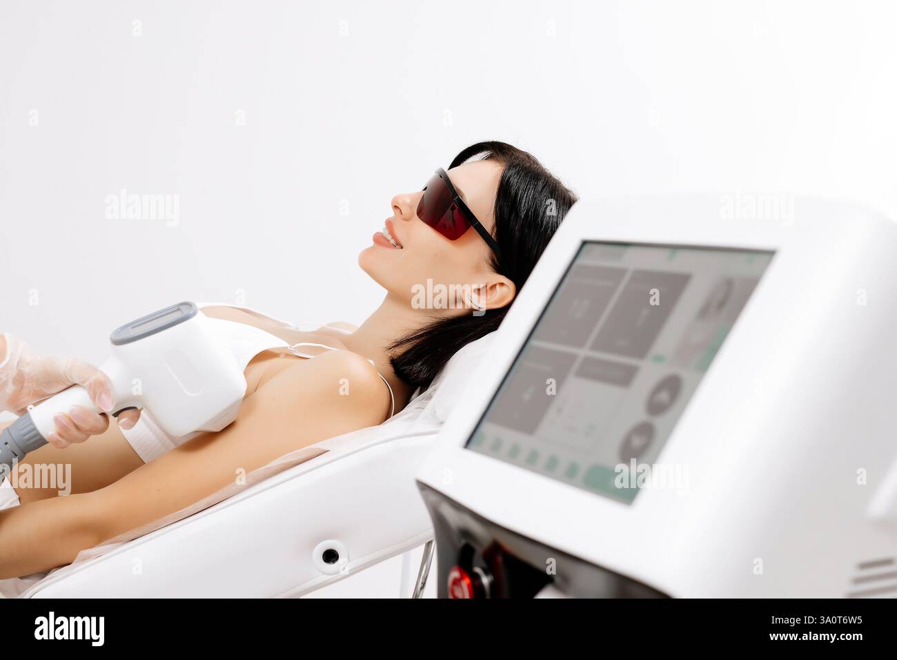 Körperhygiene. Laserhaarentfernung des Körpers. Ein Kosmetiker entfernt Körperhaare junger Frauen. Laserhaarentfernung in einer Kosmetikklinik. Stockfoto Körperhygiene. Laserhaarentfernung des Körpers. Ein Kosmetiker entfernt Körperhaare junger Frauen. Laserhaarentfernung in einer Kosmetikklinik. Stockfoto
