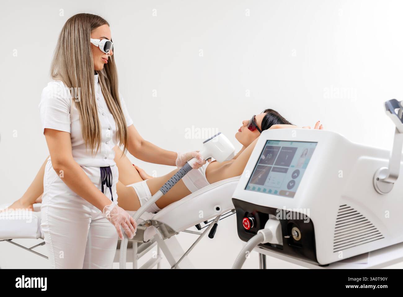Körperhygiene. Laserhaarentfernung des Körpers. Ein Kosmetiker entfernt Körperhaare junger Frauen. Laserhaarentfernung in einer Kosmetikklinik. Stockfoto Körperhygiene. Laserhaarentfernung des Körpers. Ein Kosmetiker entfernt Körperhaare junger Frauen. Laserhaarentfernung in einer Kosmetikklinik. Stockfoto