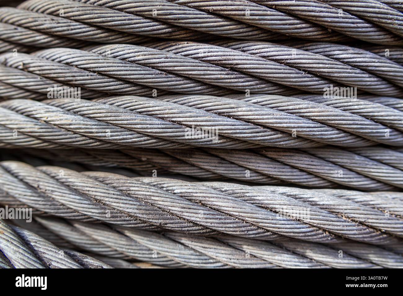 Nahaufnahme eines metallischen Kabels, das ordentlich mit leichter Krümmung gewickelt ist und häufig zum Schleppen von Schiffen und in Hängebrücken verwendet wird, komplizierte Details Stockfoto