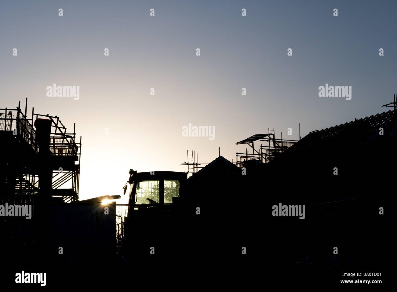 Ein Wohnhaus, das mit Gerüsten gebaut wird, die von der Sonne umrahmt wurden, Großbritannien Stockfoto