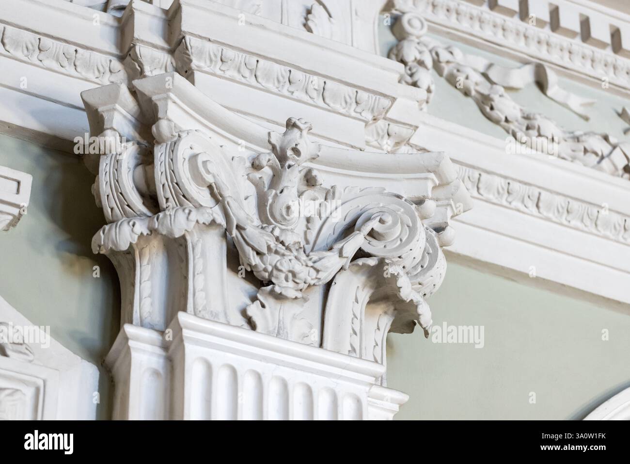 Aufwendig gestaltete barocke Verzierungen an einer Wand mit weißen klassischen dekorativen Details. Säulenspitze und dekorierter Säulengang Stockfoto Aufwendig gestaltete barocke Verzierungen an einer Wand mit weißen klassischen dekorativen Details. Säulenspitze und dekorierter Säulengang Stockfoto