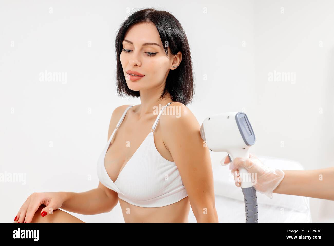 Körperhygiene. Laserhaarentfernung des Körpers. Ein Kosmetiker entfernt Körperhaare junger Frauen. Laserhaarentfernung in einer Kosmetikklinik. Stockfoto Körperhygiene. Laserhaarentfernung des Körpers. Ein Kosmetiker entfernt Körperhaare junger Frauen. Laserhaarentfernung in einer Kosmetikklinik. Stockfoto