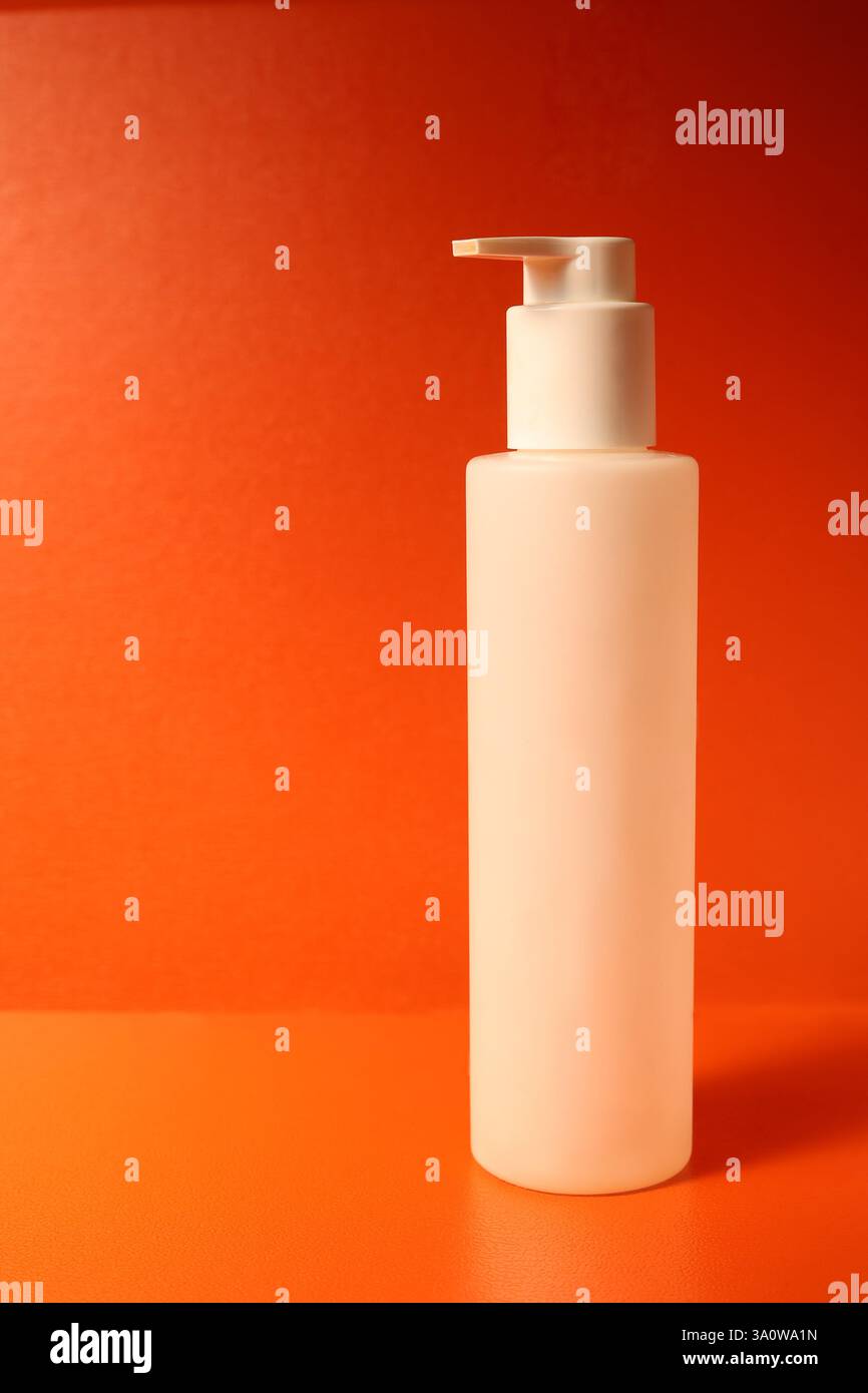 Weiße Flasche für Hautpflegeprodukt für Gesichtspflegeprodukt Gesichtsspülung Flasche Gesichtsspülung mit Spender auf orangem Hintergrund. Stockfoto