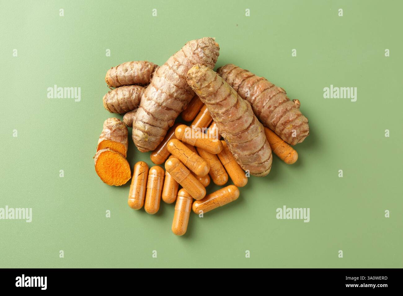 Kurkuma-Rhizome und -Kapseln auf grünem Hintergrund, flache Lagen Stockfoto