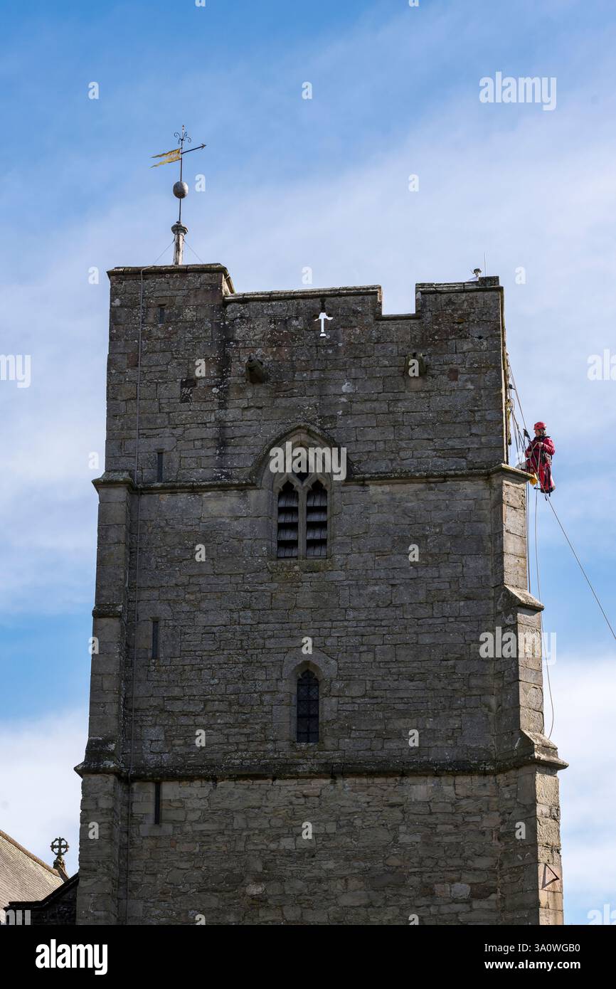 Der 77 Jahre alte Turmjäger Chris Milford hoch auf dem mittelalterlichen Turm der St. Andrew's Church, Presteigne, Powys, entfernt die alte 19c-Uhr für Renovierung und Regilding (Wales, Großbritannien). Chris arbeitet für WallWalkers Ltd. Aus Bristol Stockfoto