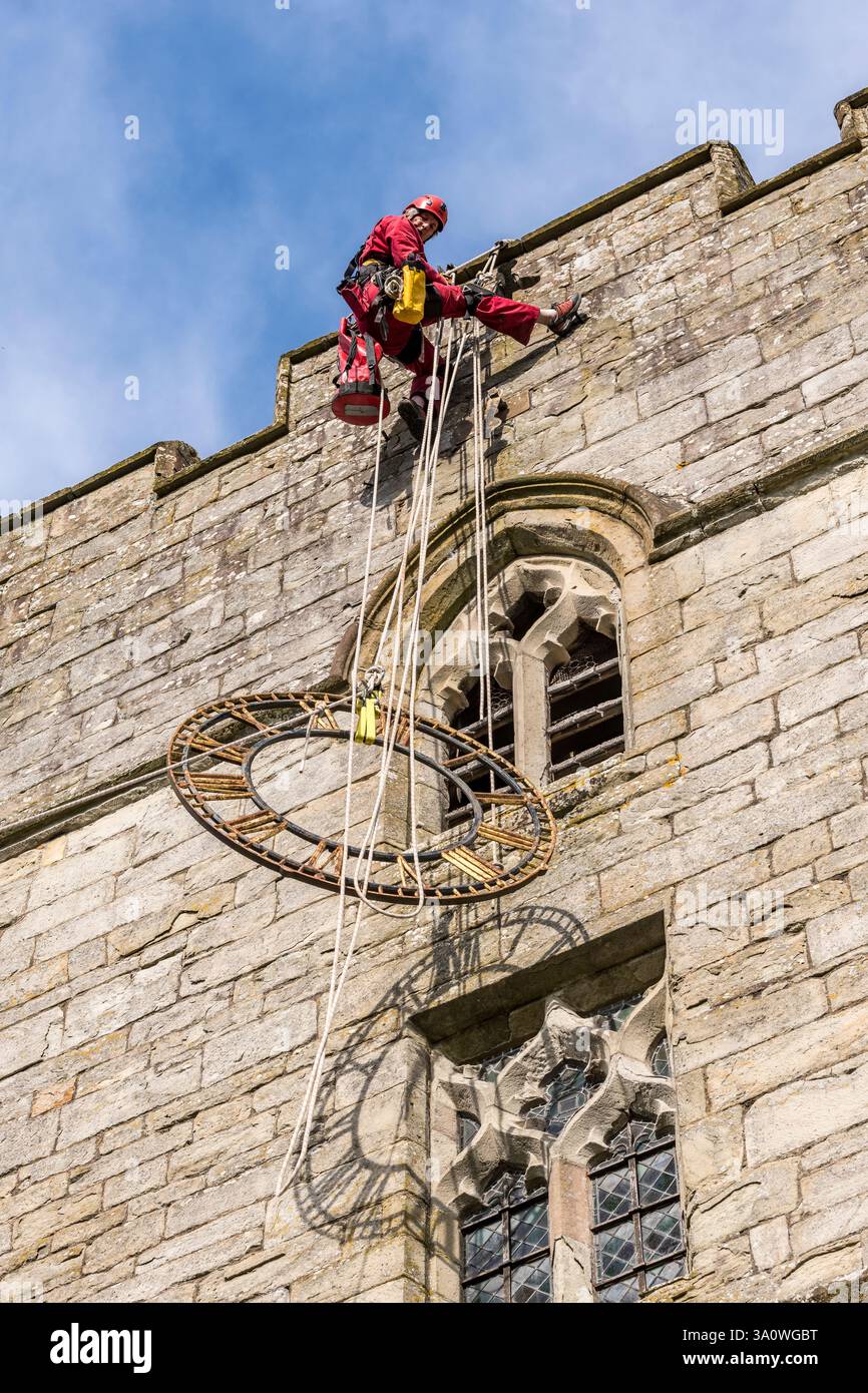 Der 77 Jahre alte Turmjäger Chris Milford hoch auf dem mittelalterlichen Turm der St. Andrew's Church, Presteigne, Powys, entfernt die alte 19c-Uhr für Renovierung und Regilding (Wales, Großbritannien). Chris arbeitet für WallWalkers Ltd. Aus Bristol Stockfoto