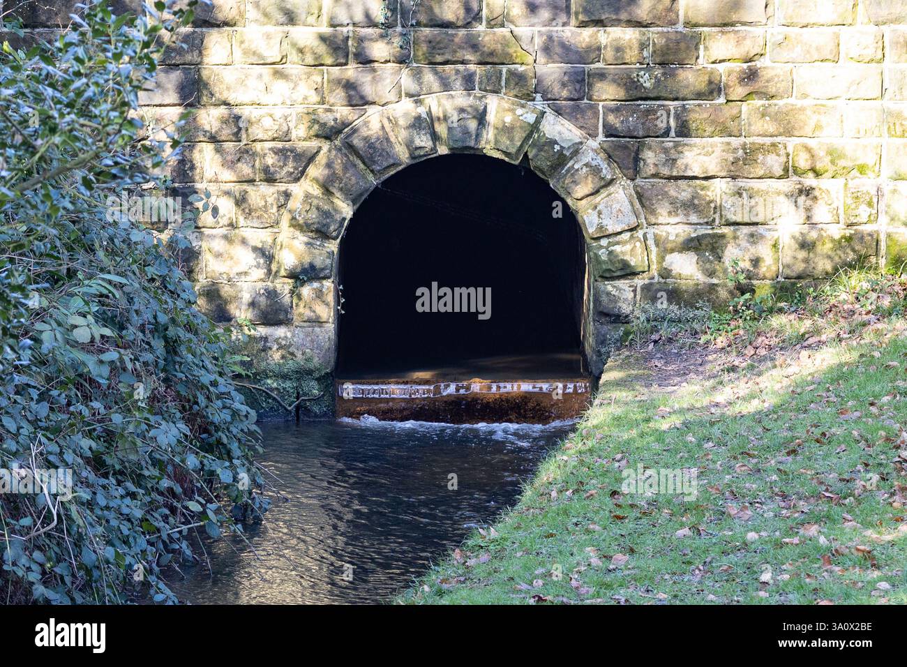 Gemauerter Tunnel, durch den der Strom läuft Stockfoto
