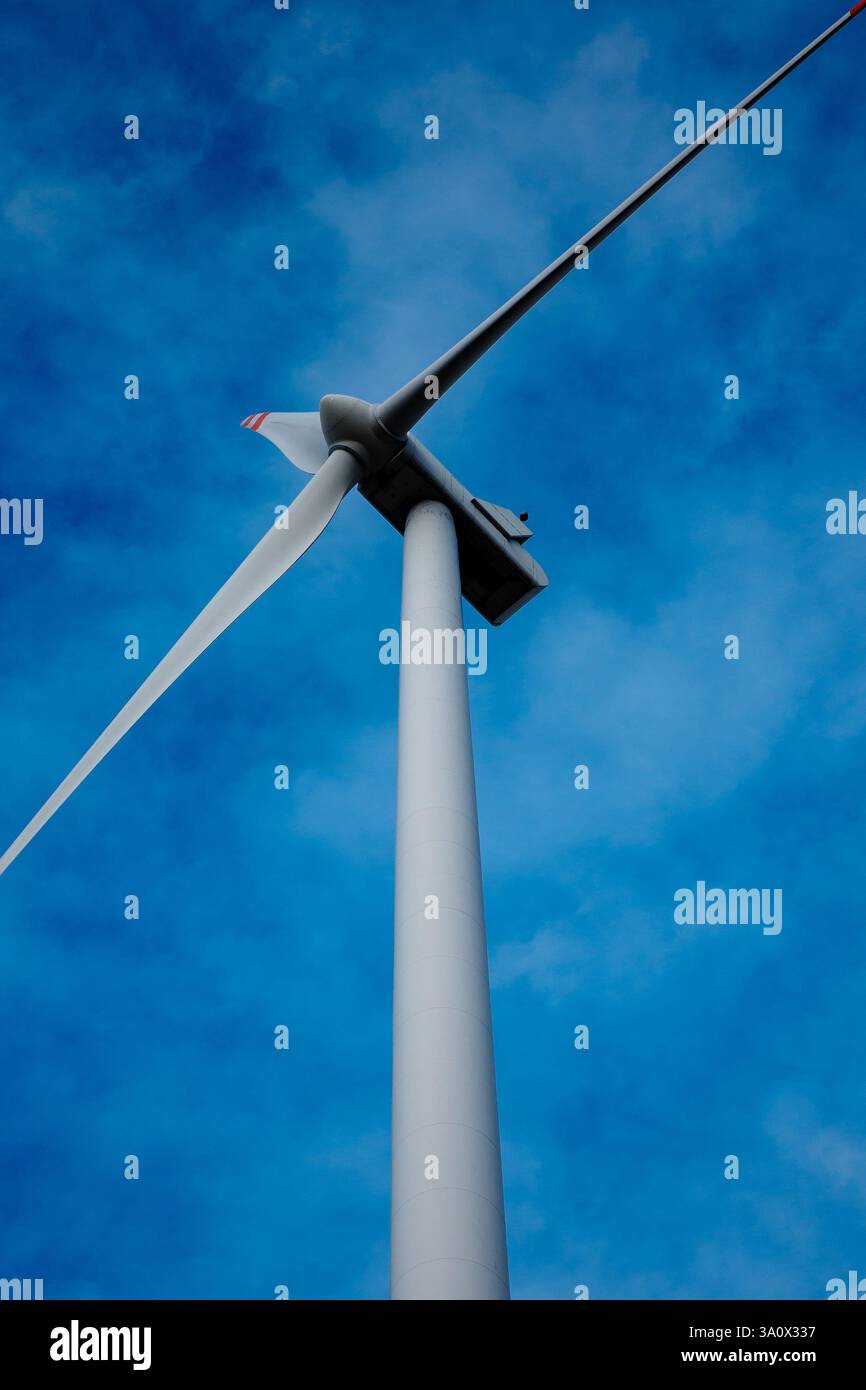 Weißer Rotor der Windenergieanlage vor blauem Himmel. Elektrischer Generator von unten fotografiert Stockfoto