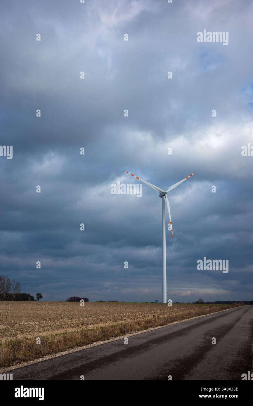Weißer Rotor der Windenergieanlage steht auf dem Feld. Weiße Wolken und blauer Himmel im Hintergrund. Stockfoto