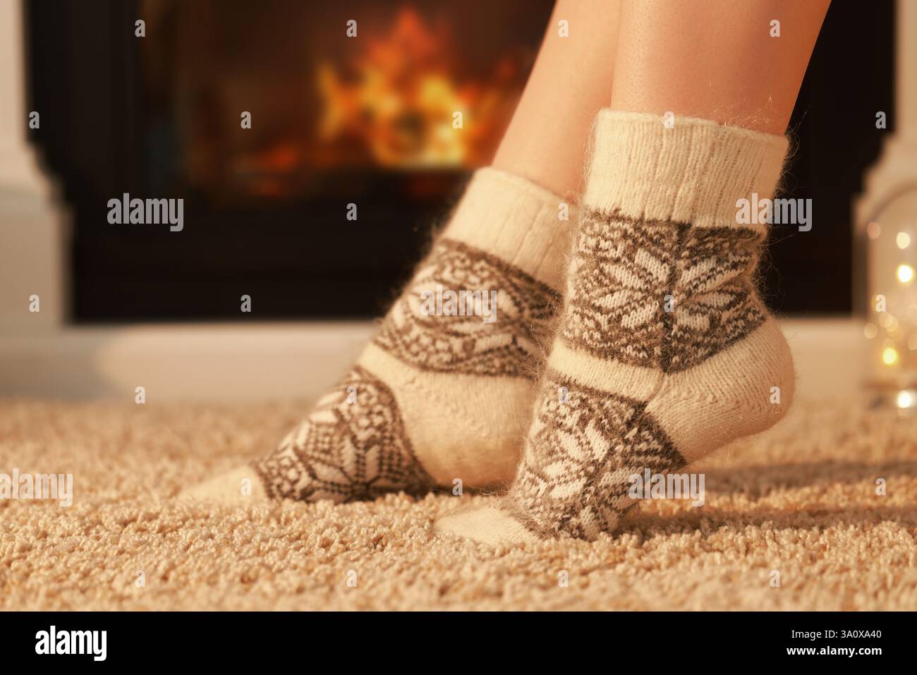Eine Frau in warmen Socken ruht sich zu Hause am Kamin aus, schließt Stockfoto