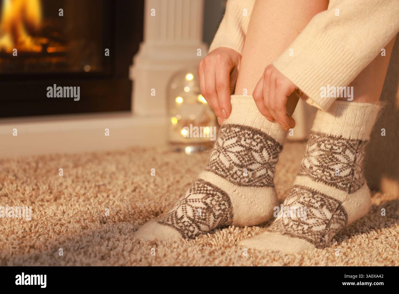 Frau in warmen Socken, die zu Hause am Kamin liegt, Nahaufnahme. Leerzeichen für Text Stockfoto