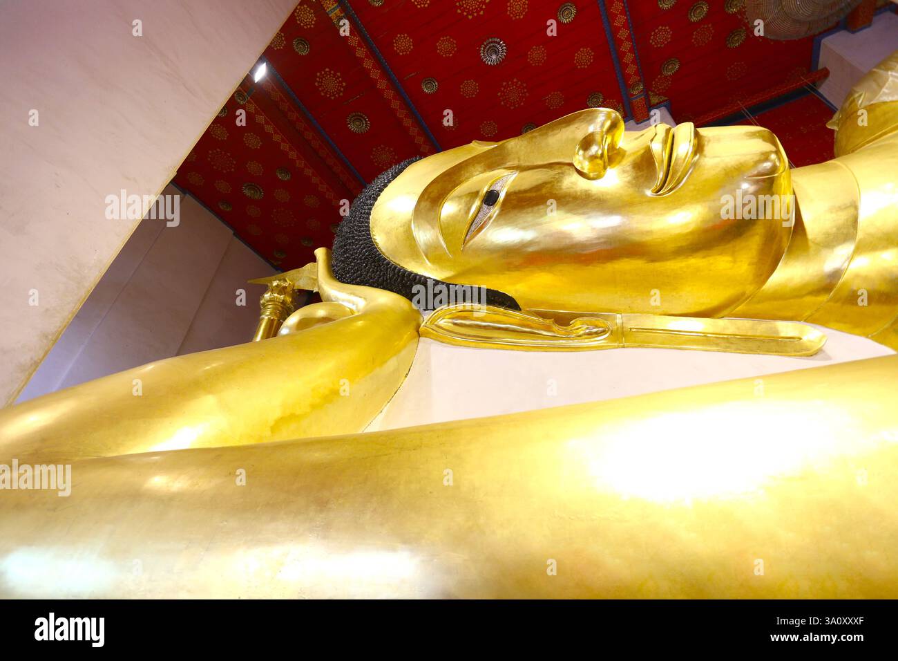 Nahaufnahme der goldenen Buddha-Statue in liegender Position, die komplizierte Details und heitere Ausdrücke erfasst, Wat Phra Non Chakkasi Worawihan-Sing Stockfoto