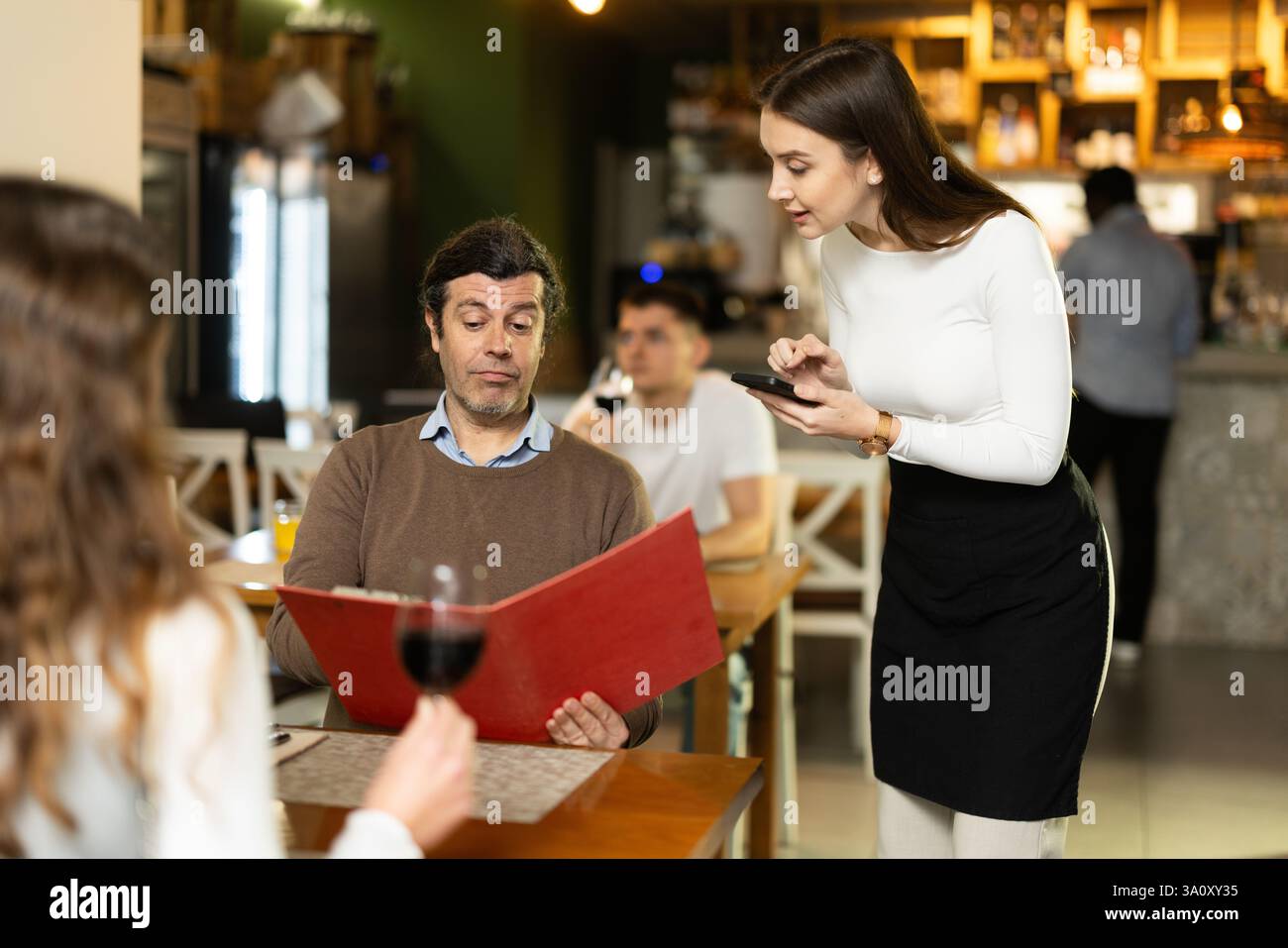 Mann, nachdem er die Speisekarte gelesen hat, bestellt er die Kellnerin Stockfoto