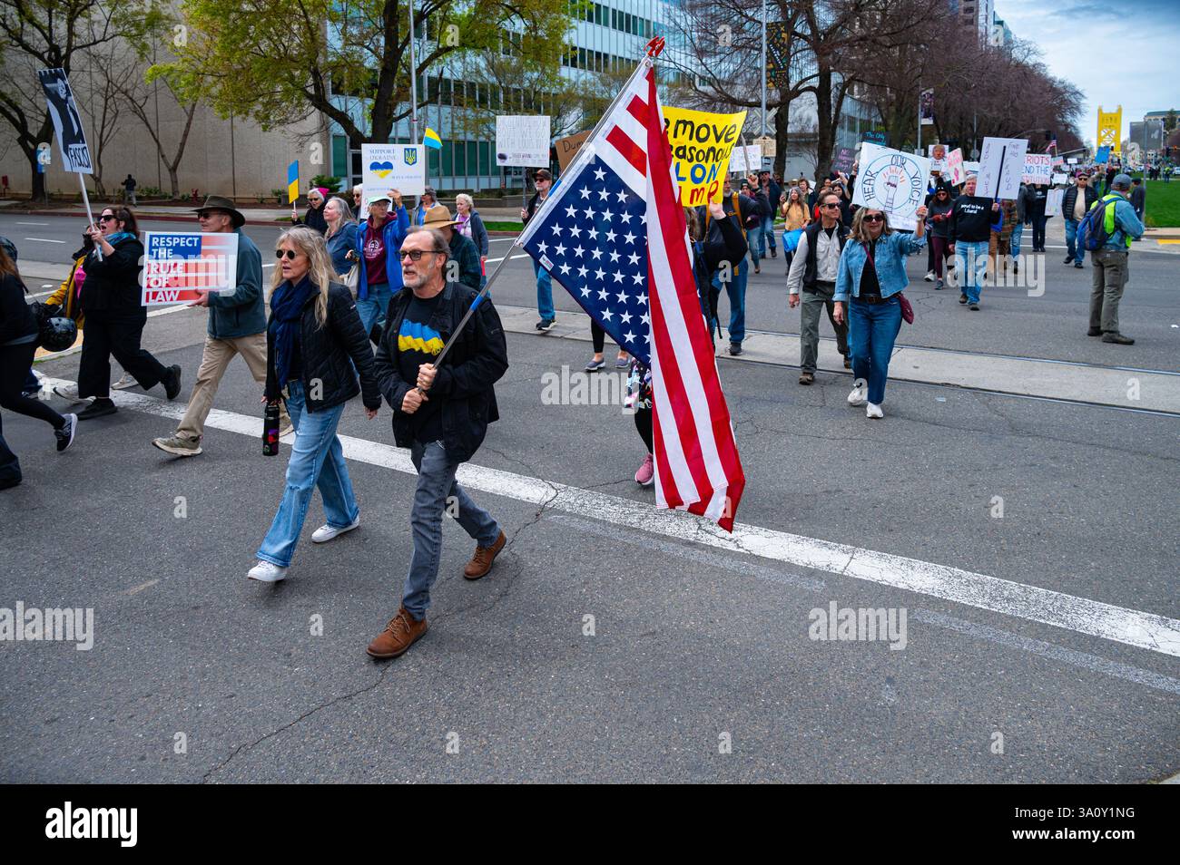 Sacramento, CA USA - 4. März 2025: Ein Mann mit umgedrehter US-Flagge marschiert während der Demokratie am 4. März 50501 in Richtung Kapitol. Stockfoto