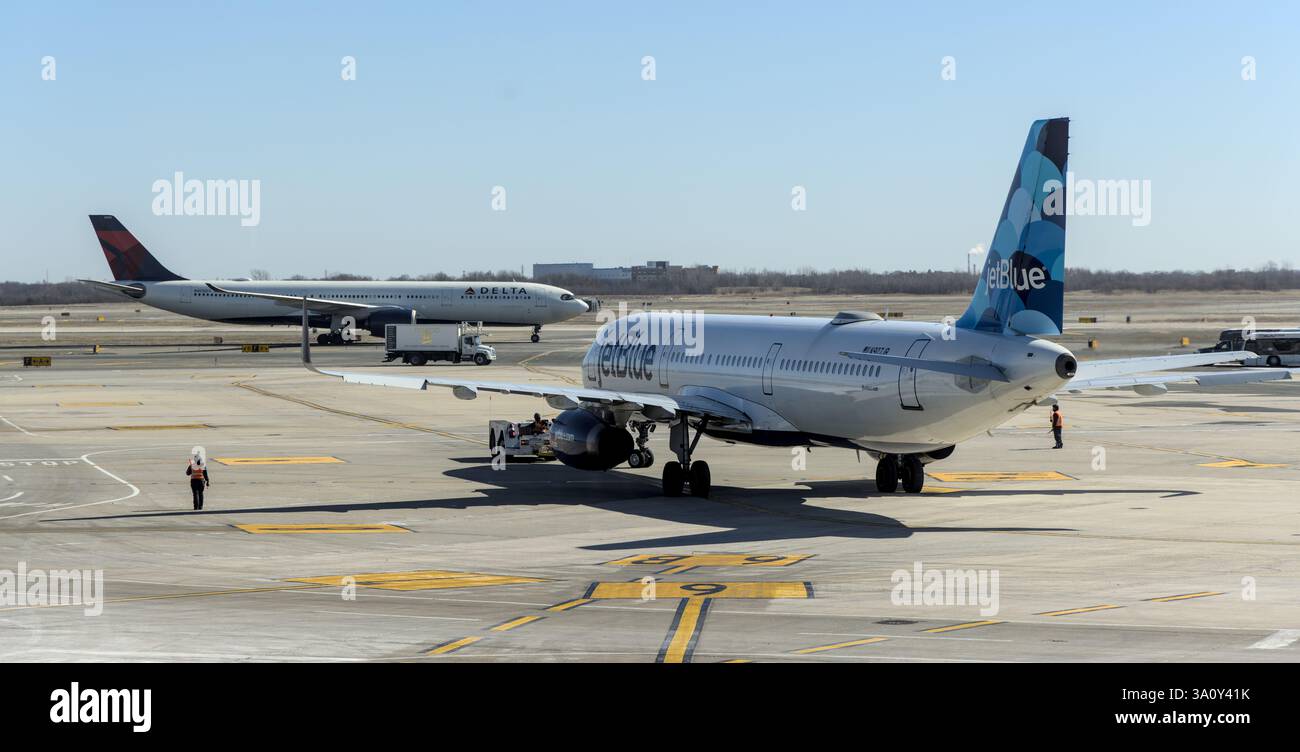 JetBlue Flugzeug auf Asphalt am JFK International Airport in Queens New York City mit Delta Flugzeug im Hintergrund. Stockfoto