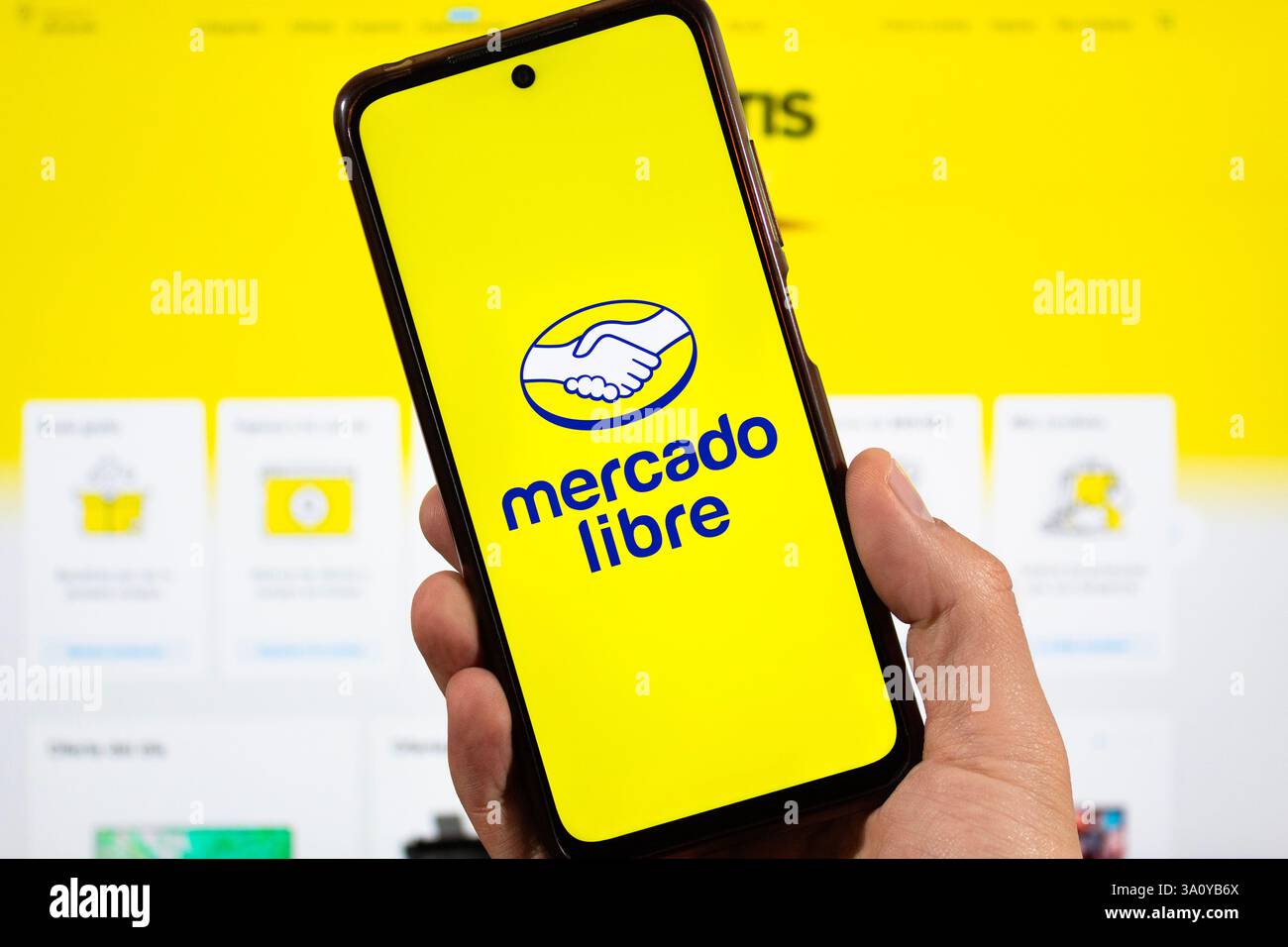 BOGOTA, KOLUMBIEN - 5. MÄRZ 2025 Eine männliche Hand, die ein Smartphone mit mercado libre e Commerce Logo und unscharfer mercado libre Oberfläche auf Backgro hält Stockfoto