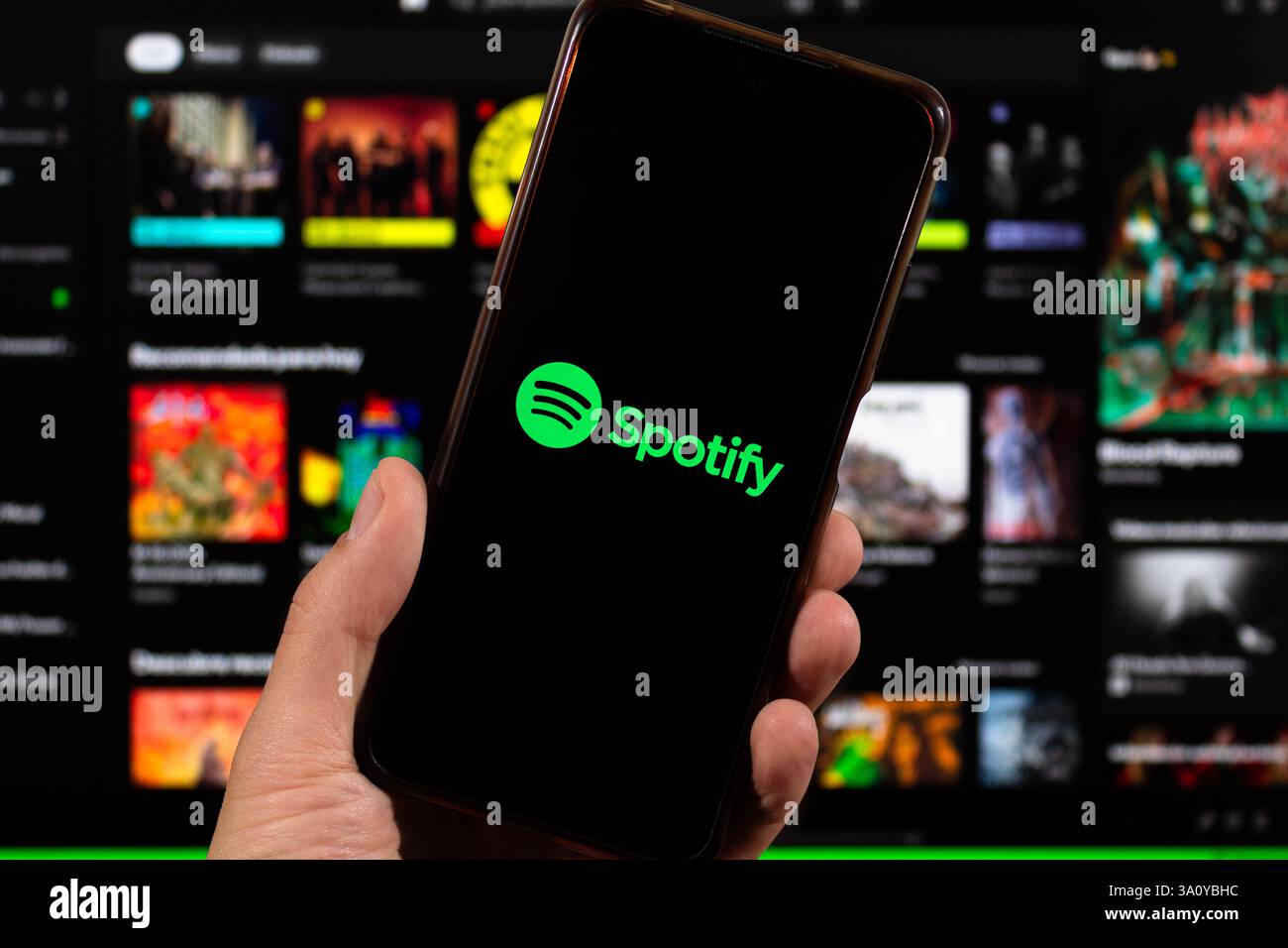 BOGOTA, KOLUMBIEN - 05. MÄRZ 2025 Makrofoto einer männlichen Hand, die ein Smartphone mit spotify-Logo und unscharfer spotify-Oberfläche im Hintergrund hält Stockfoto