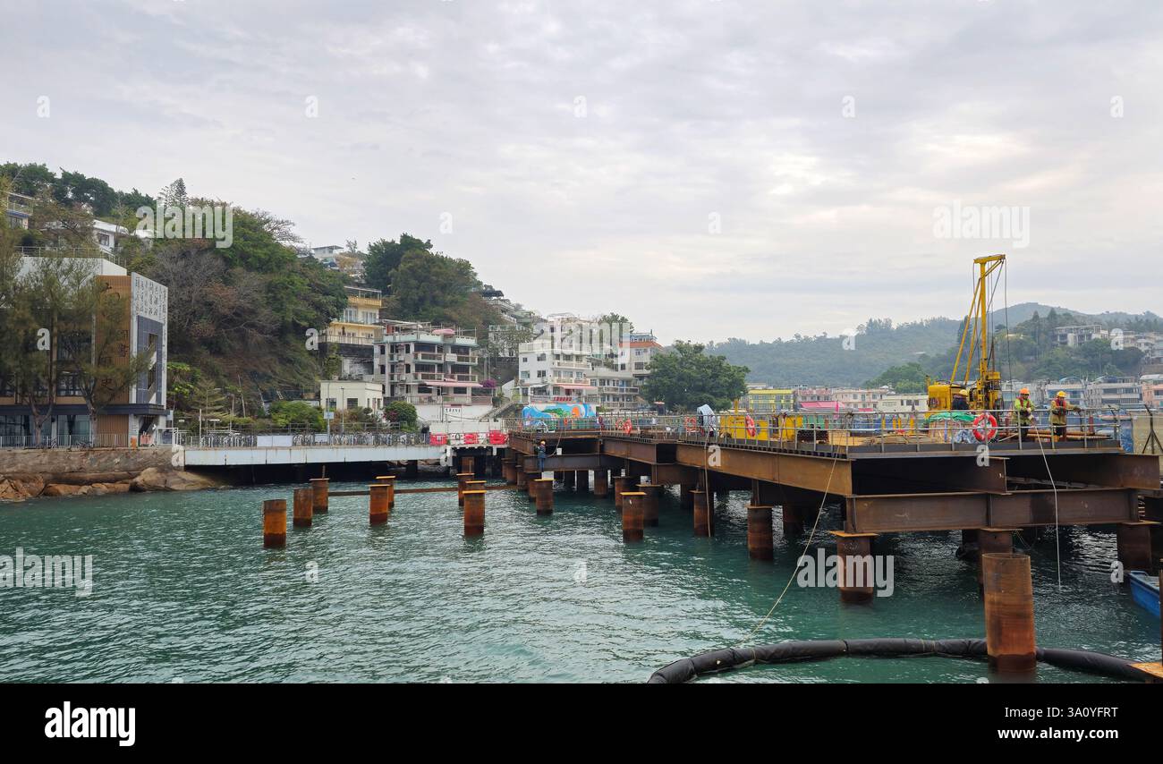 Februar 2025, Yung Shue Wan, Lamma Island, Hongkong. Bauarbeiter, die am neuen Pier arbeiten. - Smartphone-aufgenommenes Stockfoto