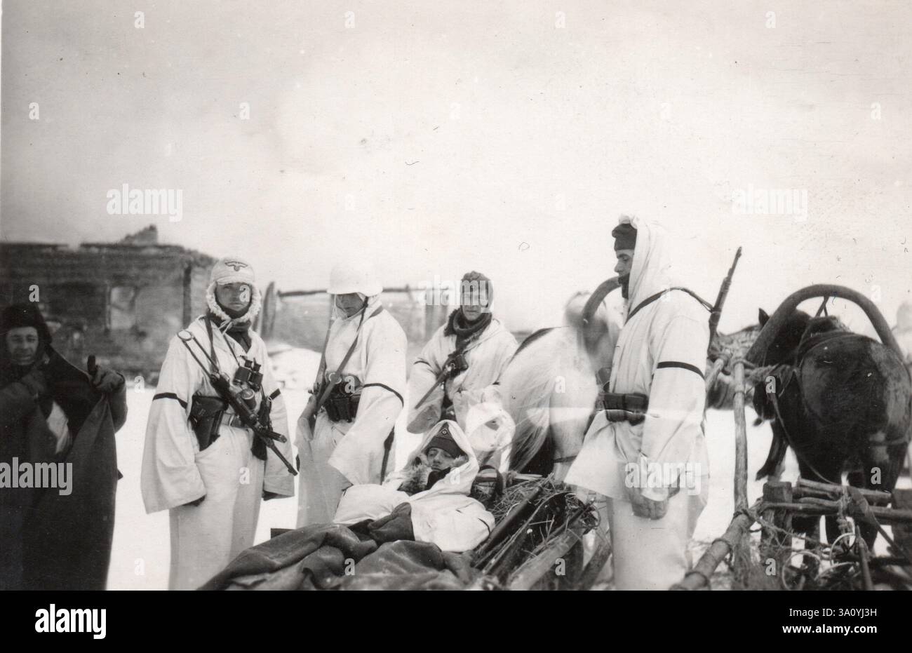 2. Weltkrieg Schwarzweißfoto deutsche Soldaten in Snow Camo mit einem verwundeten Kameraden auf einem Schlitten an der Russischen Front 1942 Stockfoto