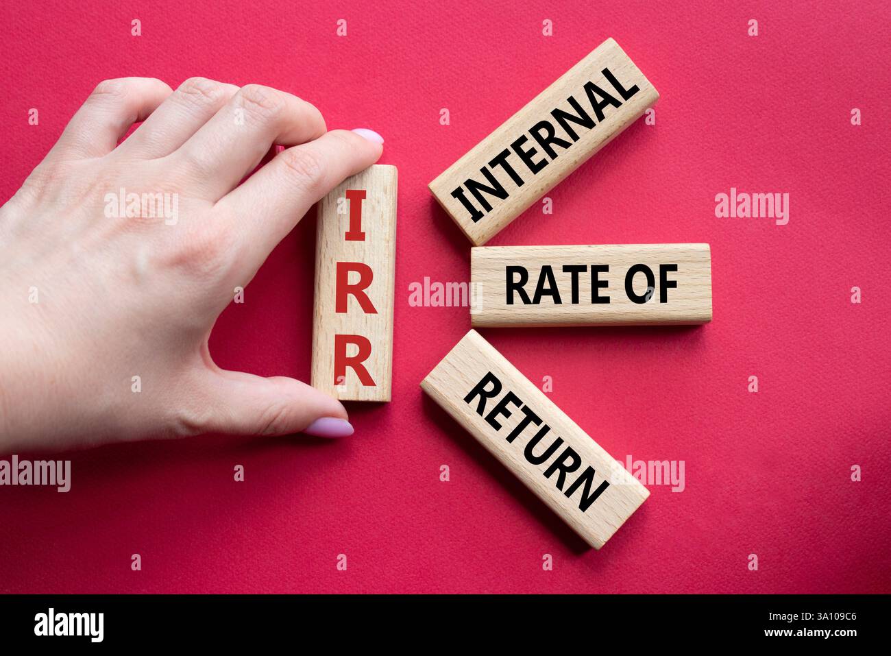 IRR – Symbol für interne Rückkehrrate. Konzeptwort IRR auf Holzwürfeln. Geschäftsmann Hand. Schöner roter Hintergrund. Business und IRR-Konzept. Spa kopieren Stockfoto