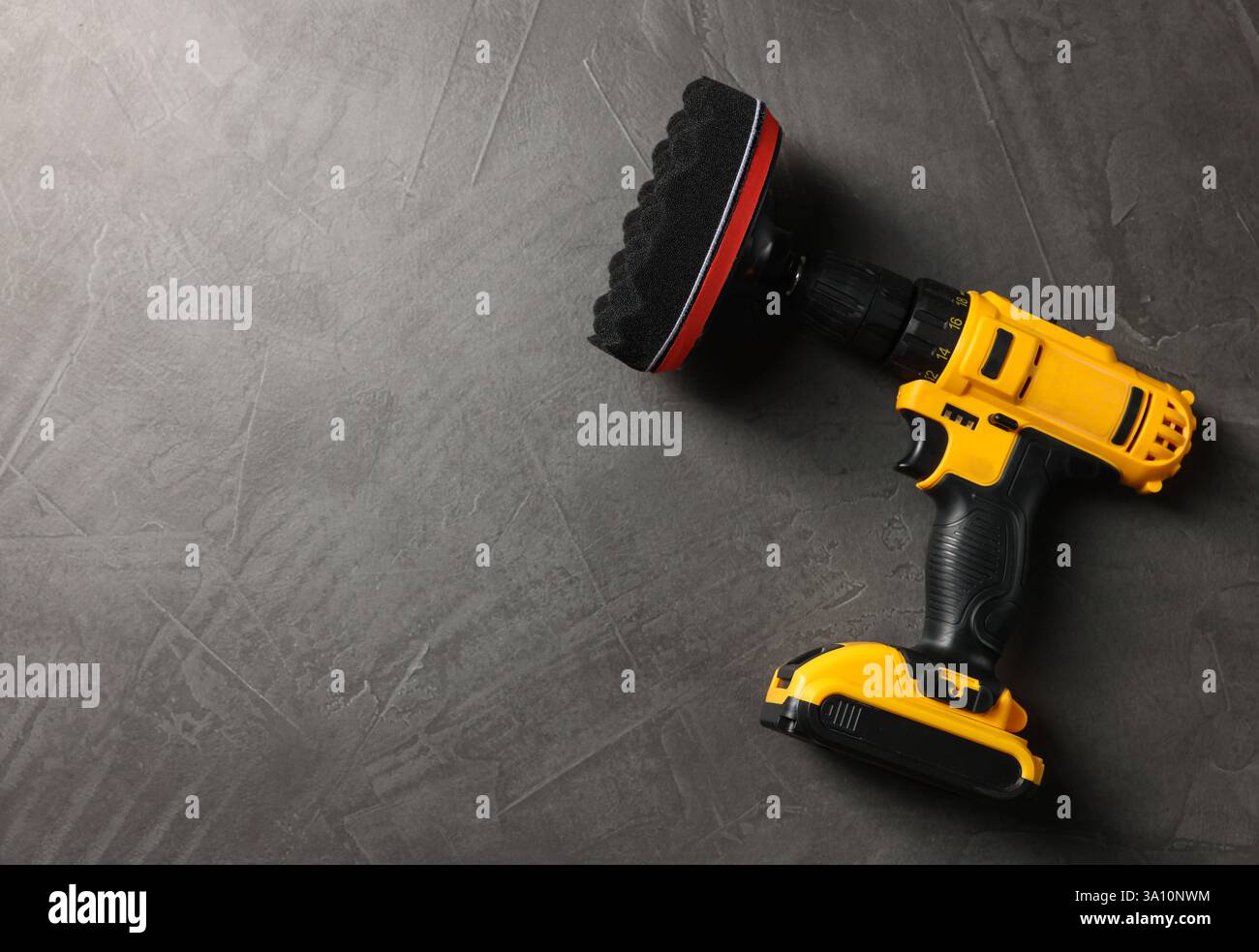 Elektrischer Schraubendreher mit polsterpolster auf grauem Tisch, Draufsicht. Leerzeichen für Text Stockfoto