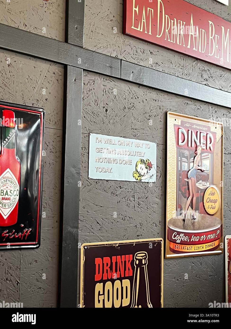 Die Wand eines Cafés ist mit einer Sammlung verspielter und lebendiger Logos und Schilder geschmückt. - Smartphone-aufgenommenes Stockfoto