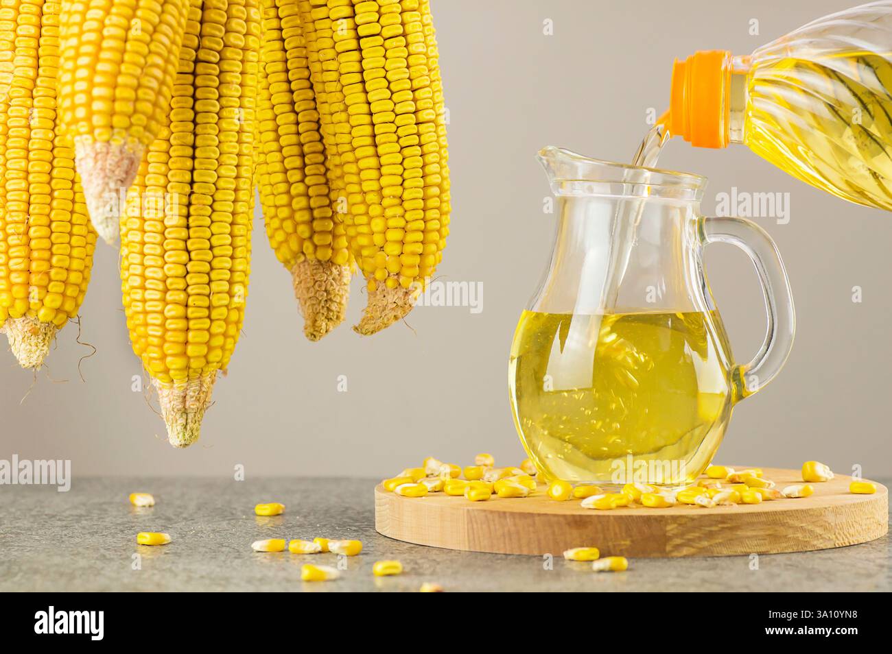 Cornflaschenöl in Glasflasche mit getrockneten Maisgroschen und Körnern auf rustikaler Kulisse gießen. Zusammensetzung des Speiseöls Stockfoto