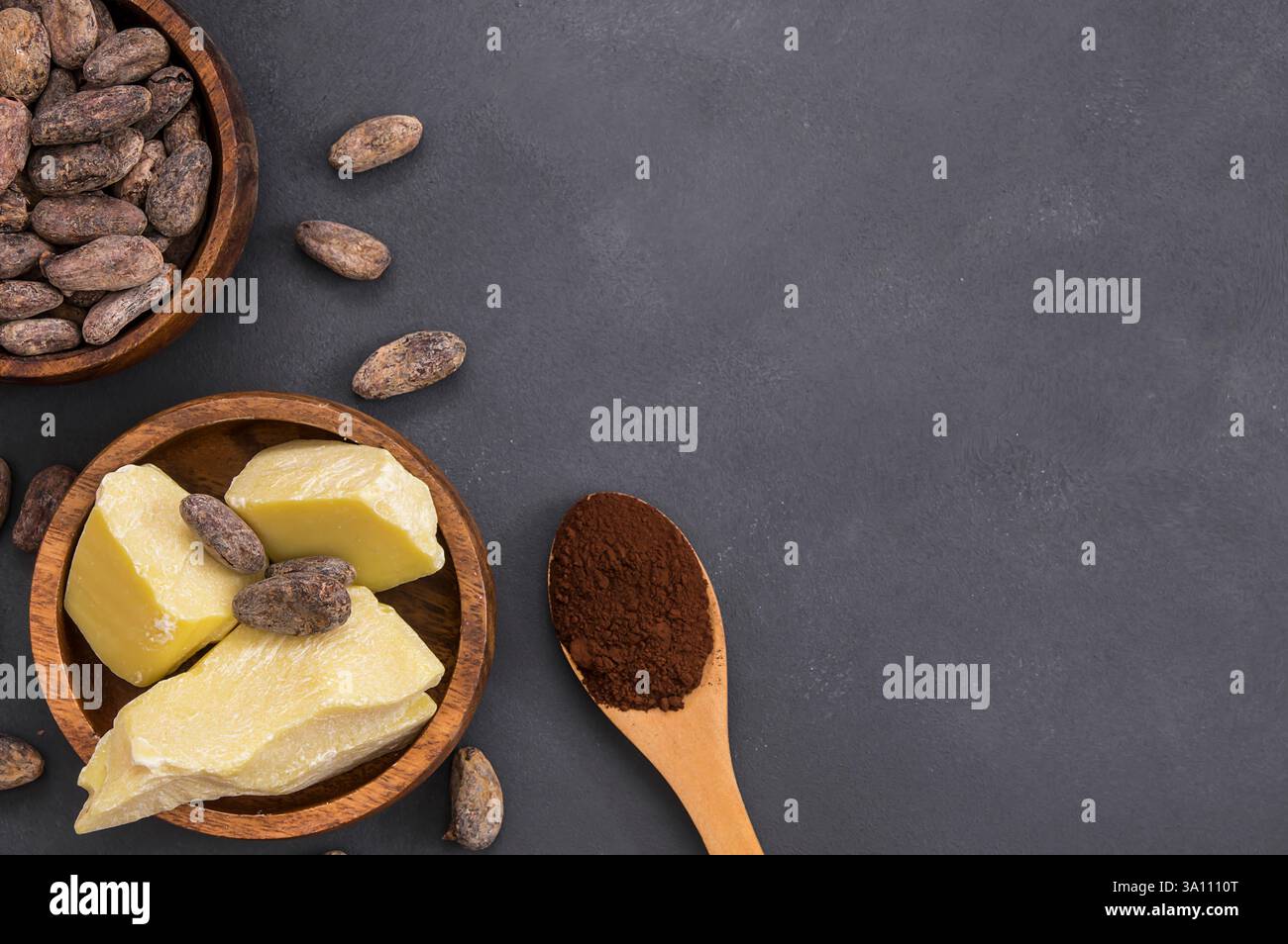 Kakaobutter oder Cocoa-Bohnen-Festöl mit Kakaopulver im Löffel und rohen Kakaobohnen in Holzschale auf rustikaler Kulisse, gesundes Naturöl Stockfoto