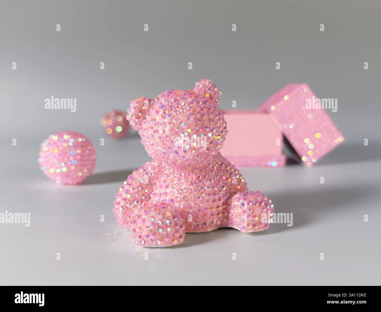 Dieses bezaubernde Bild zeigt einen glitzernden rosa Teddybär, der mit zahlreichen kleinen Edelsteinen verziert ist. Die Edelsteine glitzern und verleihen den Gegenständen eine magische, skurrile Stockfoto