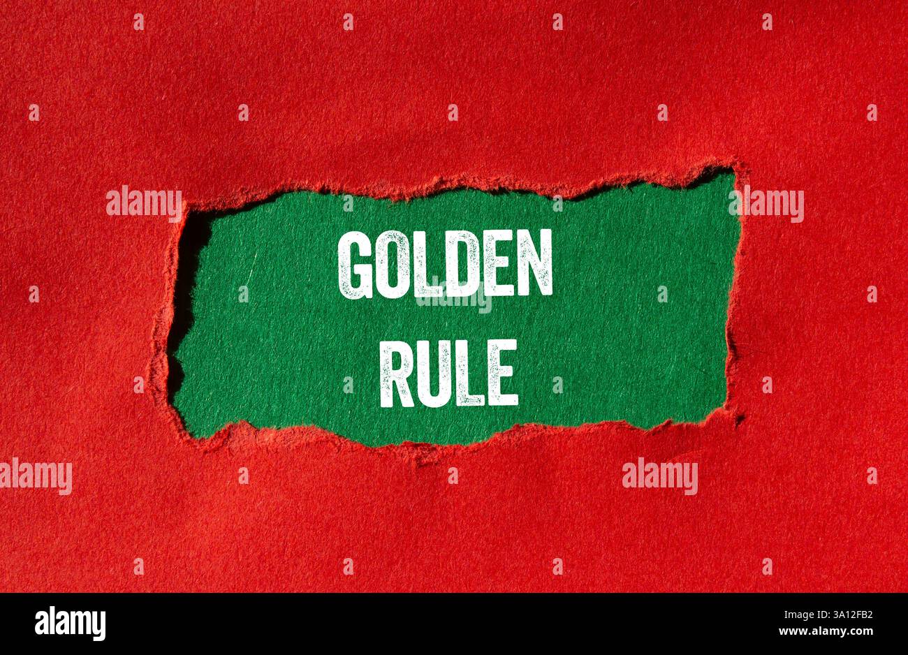 Goldene Regelnachricht auf gerissenem rotem Papier auf grünem Hintergrund. Konzeptionelles goldenes Regelsymbol. Kopierbereich. Stockfoto