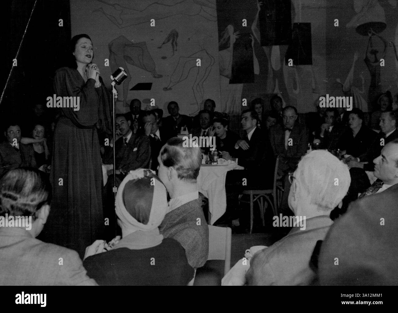 Lucienne Boyer, mit dem Lied „Parlez moi d'amour“, zieht jeden Abend ein volles Haus im „Cafe Societe“ Uptown an. Die Wandmalereien wurden von dem französisch-amerikanischen Maler Anton Refrigier erstellt. März 1954. (Foto: France Media Agency). Stockfoto