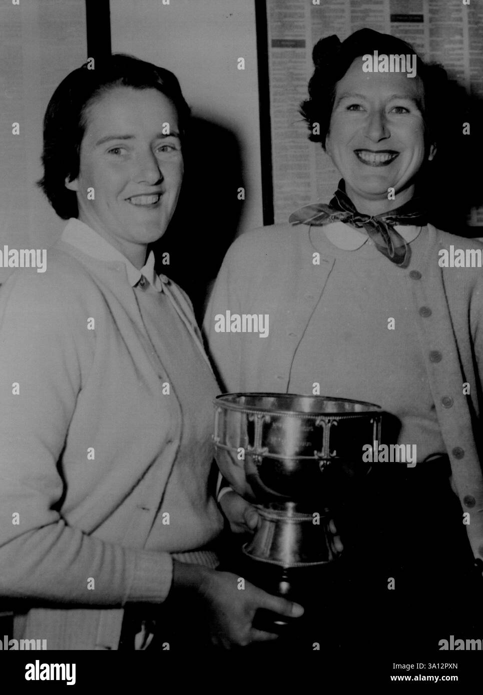 Siebter Sieg – Miss Maxine Bishop (links) hält fröhlich den West Australian Women's Golf Championship Cup, den sie gestern zum siebten Mal gewann, als sie Mrs. G. Keall (rechts) besiegte. September 1954. Stockfoto