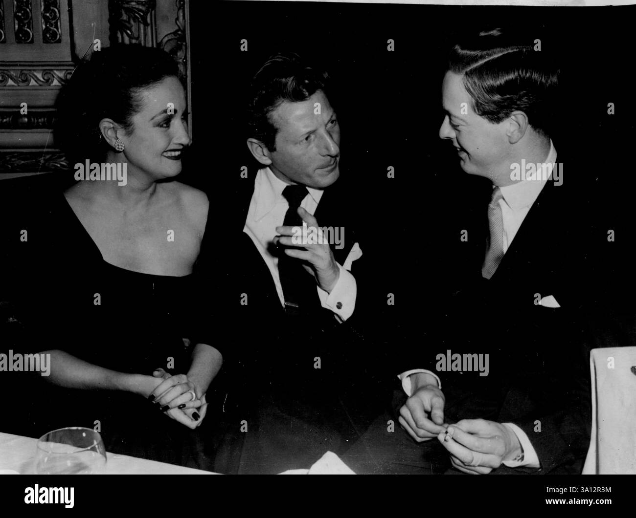 Abschiedsessen -- der amerikanische Filmstar Danny Kaye führt ein freundliches Gespräch mit dem Marquess of Blandford bei einem Abschiedsessen, das dem Komiker am Vorabend seiner Abreise nach Amerika gegeben wurde. Er hatte gerade eine Verlobung mit dem London Palladium Theatre abgeschlossen. Dorothy Lamour, Danny Kaye und der Marquess of Blandford unterhalten sich im 21-Zimmer. Doppelparty -- die schwulste Feier in London gestern Abend war ein Doppelevent. Es war, um Dorothy Lamours Eröffnungsabend im Palladium zu feiern und eine Abschiedsparty von Danny Kaye, der morgen in der Queen Elizabeth in die USA zurückkehrt. Mai Stockfoto