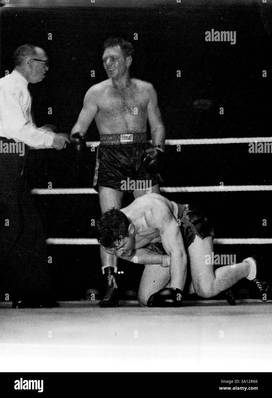 Woodcock buhte aus dem Ring -- wie der große Kampf endete - Woodcock auf seinen Knien in Qualen, nachdem Savold in der vierten Runde einen bösartigen rechten Oberschnitt geschwungen hatte. Schiedsrichter Russell entschied den Schlag als Foul und schickte den Amerikaner in seine Ecke und verlieh den Kampf an Woodcock. Es ist bekannt, dass Tom Hurst, Woodcocks Manager, einen Kampf mit Johnny Ralph aus Südafrika in Johannesburg arrangieren könnte. Dezember 1948. Stockfoto