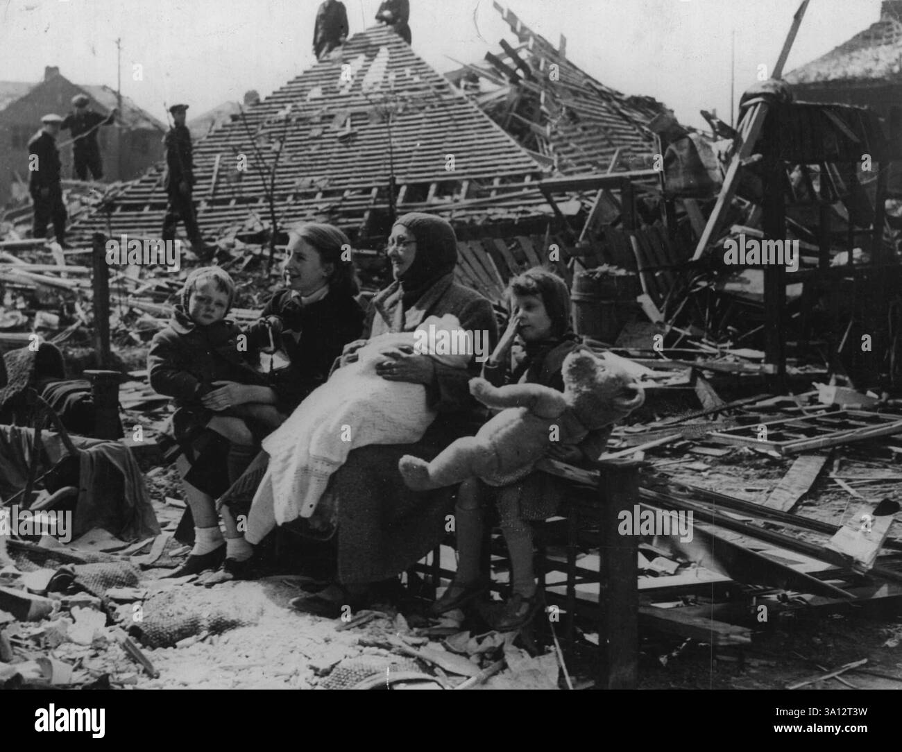 Die 68-jährige Mrs. Sarah Manson sitzt auf dem Wrack ihres Heims in Liverpool. Als eine Bombe das Haus zerstörte, rettete sie ihre vier Enkelkinder, die sie auf diesem Bild gesehen hat. In ihren Armen ist die 4 Monate alte Dorothy May. B.M.I., SEPTEMBER 1941. Juli 1947. (Foto vom United Kingdom Information Office). Stockfoto