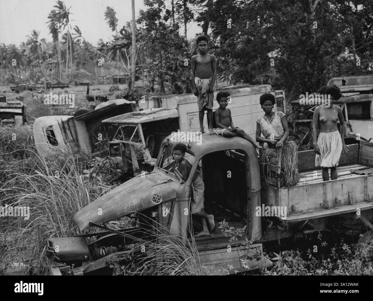 Neuguinea Special - Milne Bay Ureinwohner-Jungs suchen nach weggeworfener Kriegsausrüstung. 7. Jahrestag der Kämpfe im August-September: Der Dschungel hat seinen eigenen zurückerobert, trotz der Arbeit der Bergungsbanden in den letzten Jahren. September 1949. (Foto: Courier-Mail). Stockfoto