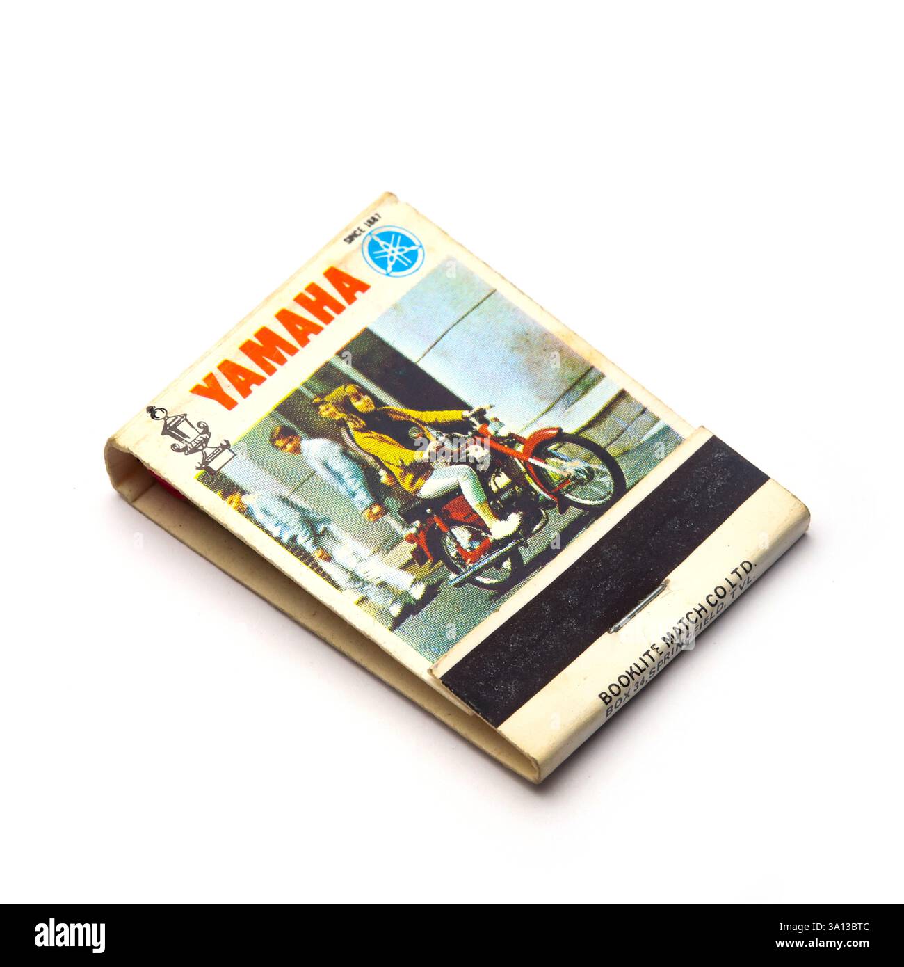 Vintage Yamaha Streichholzschachtel mit einem stilvollen Motorradfahrer auf einer Straße in sonniger urbaner Umgebung in den 1960er Jahren Stockfoto