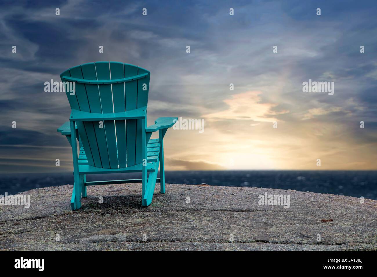 Leerer Adirondack Stuhl, auf einem großen Felsen, mit Blick auf den Sonnenuntergang am Horizont Stockfoto