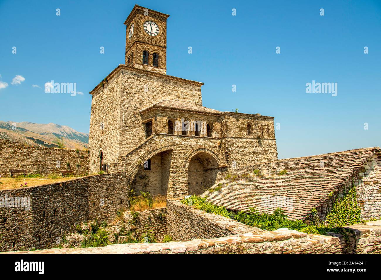 Bogenförmiger Zugang zum Gjirokaster-Uhrenturm: Eine steingeschmiedete albanische Festung, die über Schieferdächern und eifebedeckten Mauern im Drino Vall steht Stockfoto